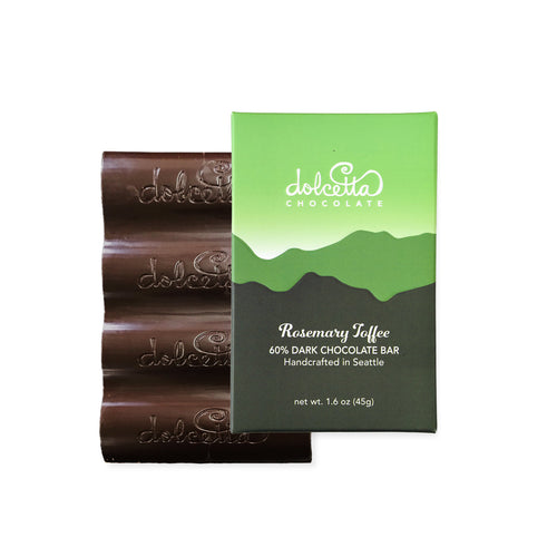 Dark chocolate bar with green packaging featuring Dolcetta Chocolate branding on a white background. | Dolcetta 60% Dark Chocolate Rosemary Toffee Bar | Made In Washington | Sweet Tooth Gifts