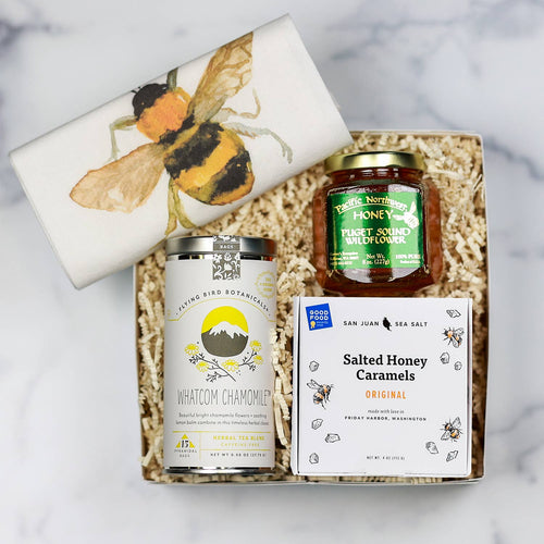 Collection of honey products including a box of salted honey caramels, a jar of honey, and a towel with a bee design. | Tea and Honey Gift Basket | Made In Washington | Local  Gifts For Teatime | Tea & Honey Gift For Tea Lovers