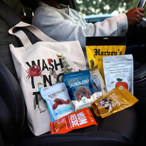 Assorted snack packages including salmon jerky, moon cheese, and popcorn with a tote bag labeled 'Washington'. 