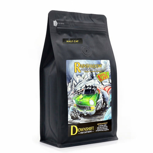 Downshift Half Caff Blend black coffee bag with colorful Rainshadow Coffee graphic design on a white background