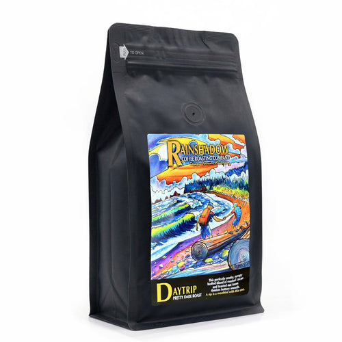 Dayrip Pretty Dark black coffee bag with colorful Rainshadow coffee label featuring a scenic design and text on a white background