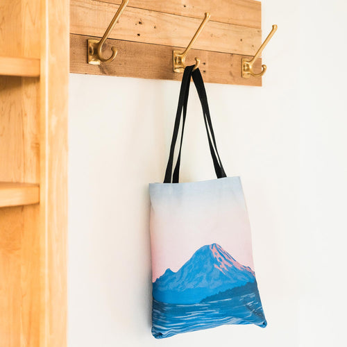 Amy Duffy tote bag with Mount Rainier alpenglow design on a wooden floor