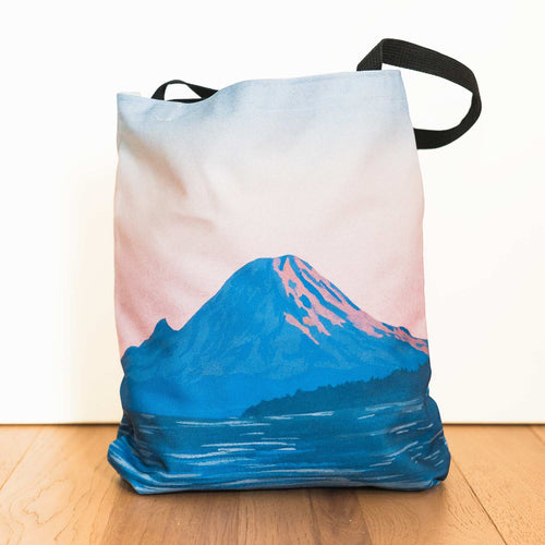 Amy Duffy tote bag with Mount Rainier alpenglow design on a wooden floor
