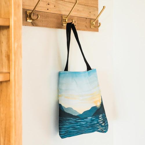 Amy Duffy Tote bag with a scenic design of mountains and sky on a wooden floor.