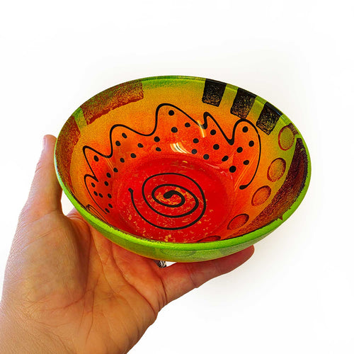 Colorful reverse painted Mardi Gras bowl with abstract design on a white background