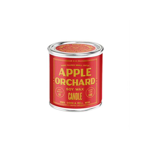 A small cylindrical candle tin with a bright red label and silver metal rim, reading 'APPLE ORCHID SOY WAX CANDLE' in yellow text, centered on a plain white background.