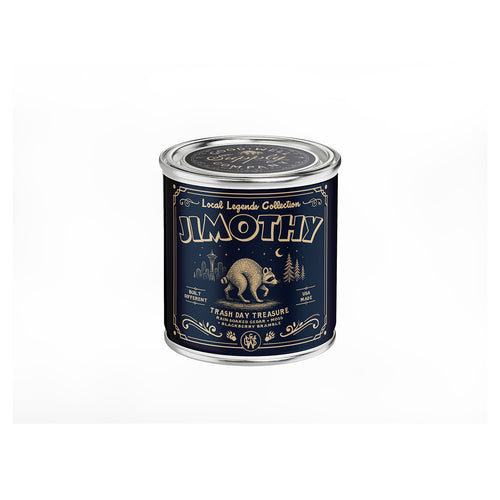 A tin candle from the Local Legends Collection called JIMOTHY, featuring a dark navy blue label with gold vintage-style text and illustrations of a racoon, trees, and a moon, set against a plain white background.