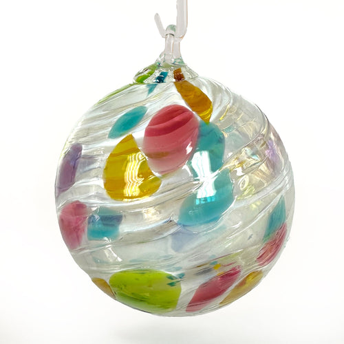 An opalescent round glass ornament with multi-color spots randomly scattered over the surface.