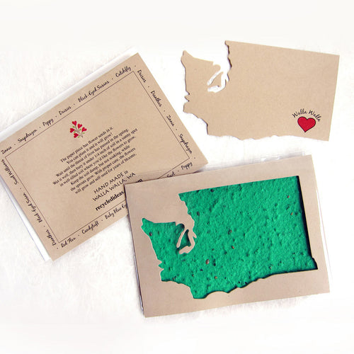 A plantable seed card featuring a turquoise blue textured shape resembling the state of Washington, beneath a cut out of the state in a light tan background.
