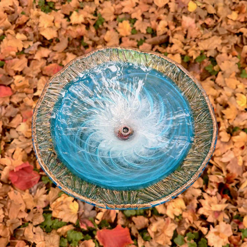 Handmade turquoise art glass birdbath basin mounted on an outdoor metal stand.