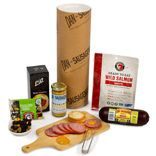 Assorted PNW food products including a cardboard tube, jars, and packages on a white background | Made In Washington State Gift Baskets | Dan The Sausageman Tube Treats