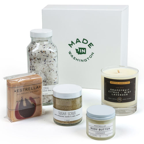 Collection of beauty products including a candle, body scrub, and body butter with a 'Made in Washington' box in the background. | Deluxe Spa Gift Basket | Made In Washington  | Local Gifts From The PNW