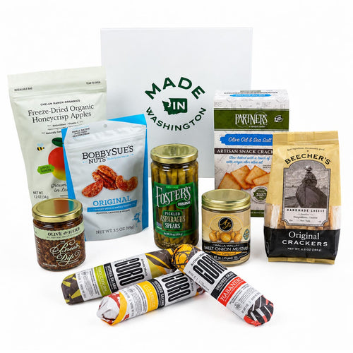 A Made in Washington charcuterie gift assortment displayed with artisan salami, crackers, pickled asparagus, dried apples, nuts, and spreads.