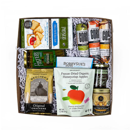 A Made in Washington charcuterie gift assortment displayed with artisan salami, crackers, pickled asparagus, dried apples, nuts, and spreads.