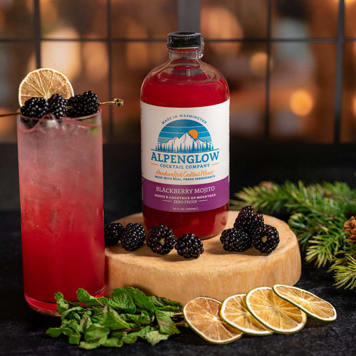 Alpenglow cocktail with blackberry mojito, garnished with lime and blackberries, on a wooden board with fresh ingredients. | Alpenglow Blackberry Mojito Drink Mixer | Made In Washington | Locally Made Cocktail Mixers