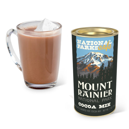 Cup of hot chocolate with a can of National Parks Cafe Mount Rainier National Park Cocoa Mix on a white background