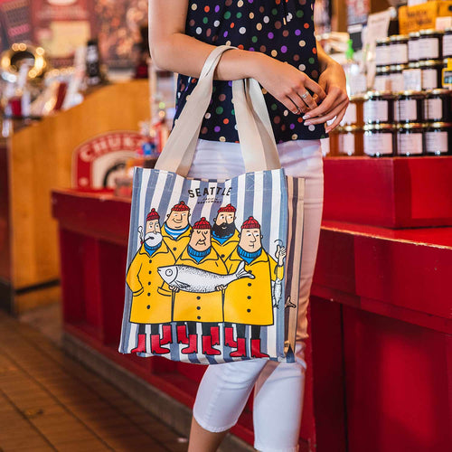 Tote bag with cartoon fishermen design and 'Seattle Pacific Northwest' text on a striped background | Chalo Seattle Fisherman Shopping Bag Blue Candy Stripe | Made In Washington