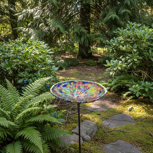 Colorful  blown glass birdbath on a white background.