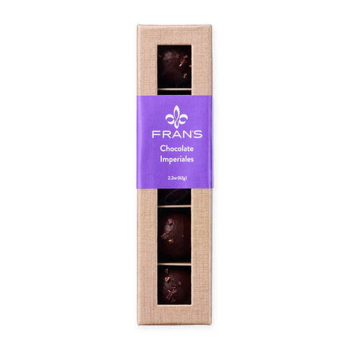 A boxed set of Frans Chocolate Imperiales chocolates in a tall, narrow champagne cardboard package with a purple label and compartments  showing the dark chocolate pieces inside, on a white background.