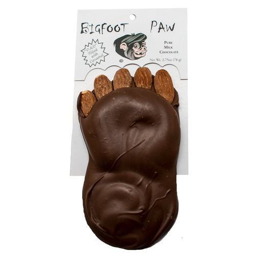A novelty Bigfoot paw-shaped chocolate on a white backing card. The chocolate is molded to look like a foot with five almond-shaped toes, and the card reads 'Bigfoot PAW' and 'Pure Milk Chocolate'.