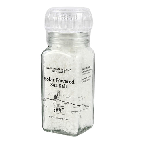 An acrylic grinder of San Juan Island Sea Salt with a clear ribbed cap, containing white salt crystals. The front label reads 'Solar Powered Sea Salt' and features a simple black line drawing of a lighthouse and waves, with the brand name 'SALT' at the bottom.