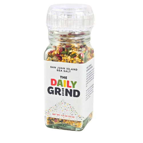 Clear acrylic jar of 'The Daily Grind' mixed spices and sea salt on a white background