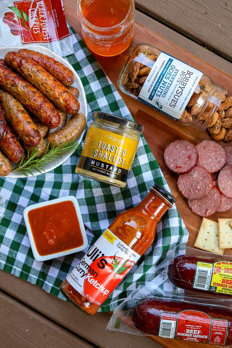 Oktoberfest food spread with grilled sausages, Dan the Sausageman summer sausage, mustard, and beer.